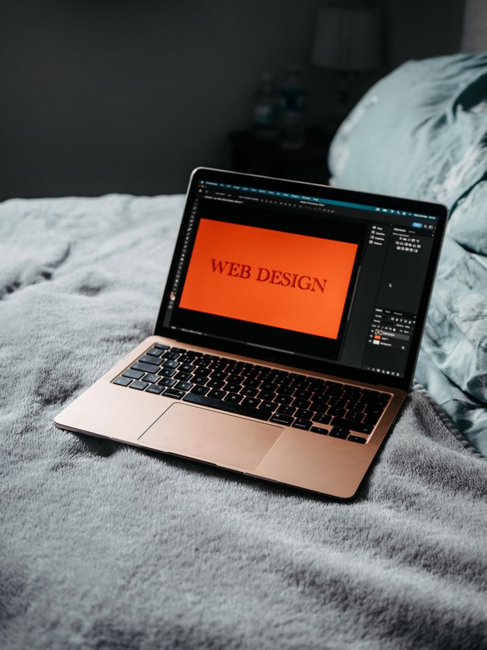 get-in-touch A laptop on a bed showing web design software, creating a cozy workspace.