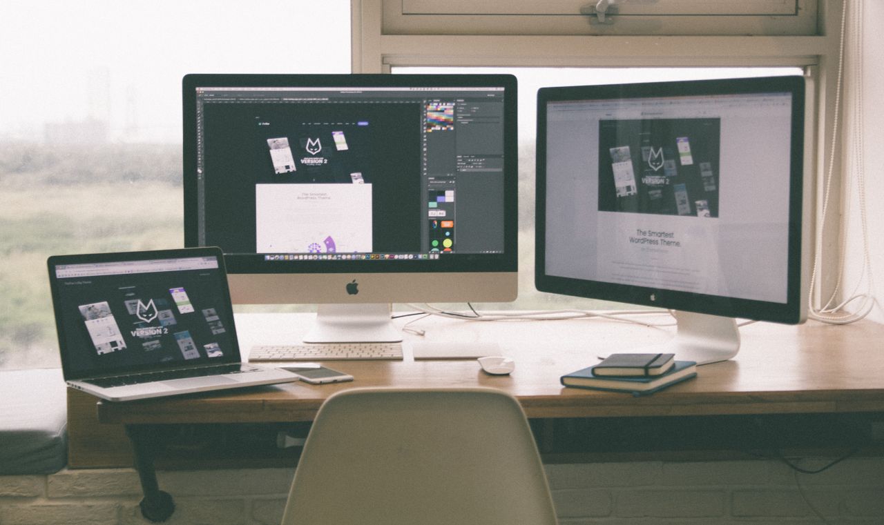 services-06 Stylish and efficient workspace with multiple monitors, laptop, and smartphone, showcasing a web design project.